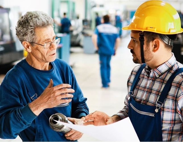 Arbeiter reden in der Produktionshalle miteinander