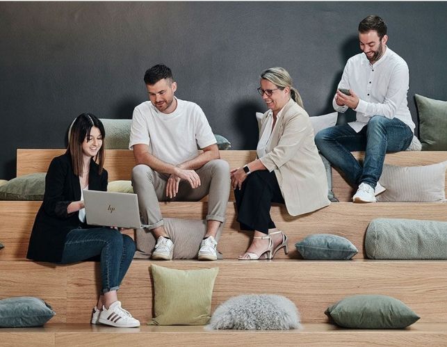 Mitarbeiter von Streit Service & Solution sitzen gemeinsam auf einer Treppe und arbeiten und sprechen miteinander