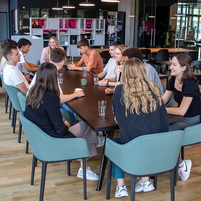 Auszubildende von Streit Service & Solution sitzen zusammen an einem Tisch und sprechen miteinander