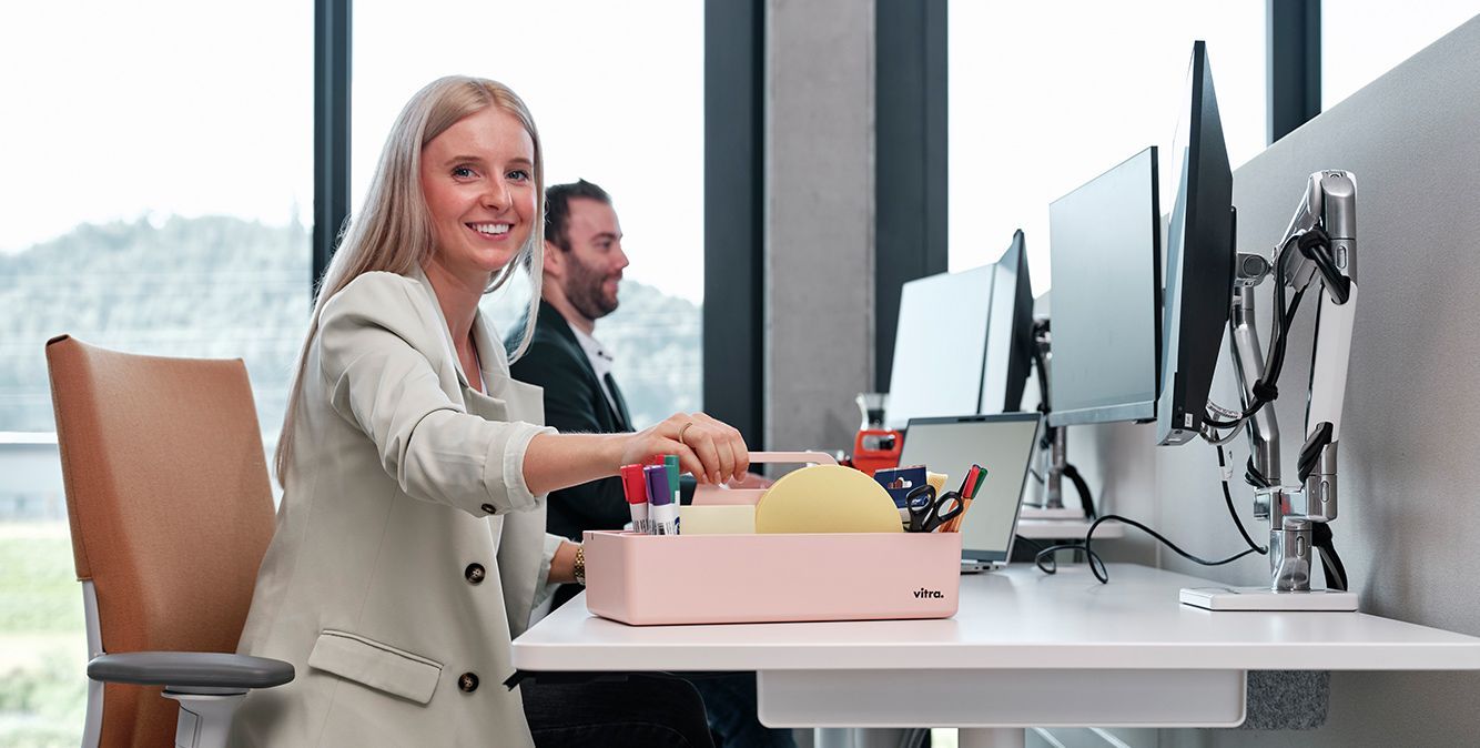 Frau mit Bürobedarfsartikeln in Toolbox am Arbeitsplatz