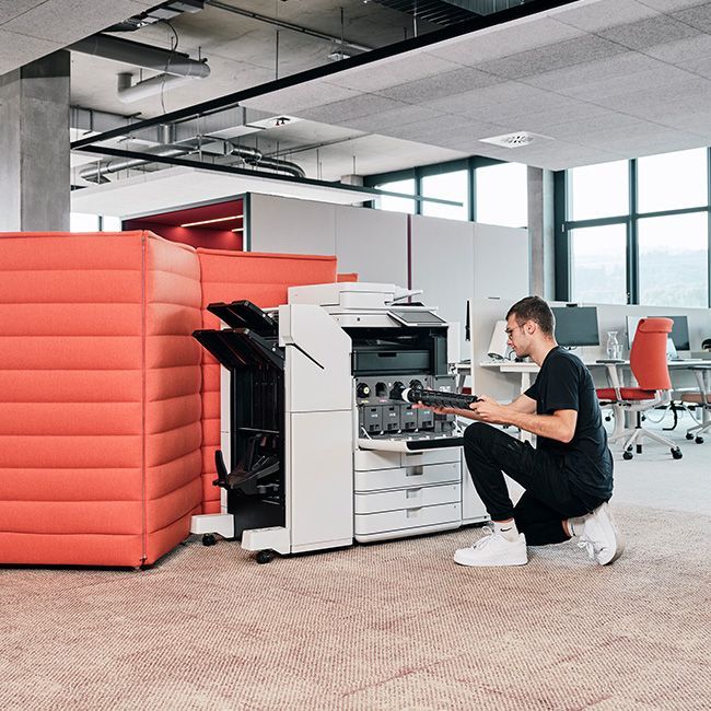 Mann tauscht kniend Toner an Drucksystem