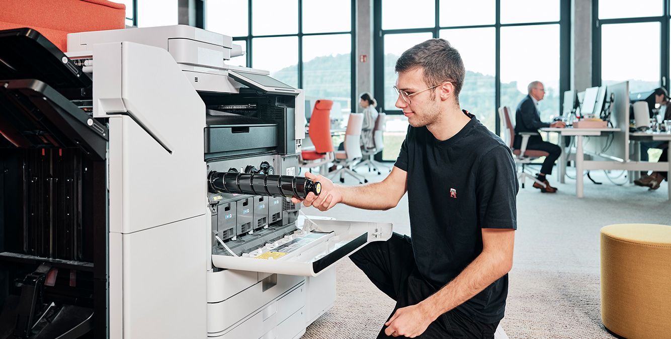 Mann kniet vor Drucksystem