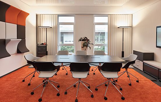 Besprechungsraum mit Tisch und Stühlen von h+h