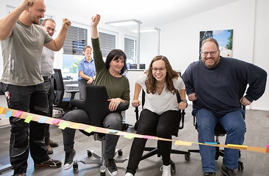 ISFORT Mitarbeiter im Büro auf Drehstühlen beim Wettrennen
