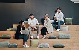 Mitarbeiter sitzen auf einer Treppe und sprechen miteinander in der Arbeitswelt von Streit Service & Solution in Gengenbach