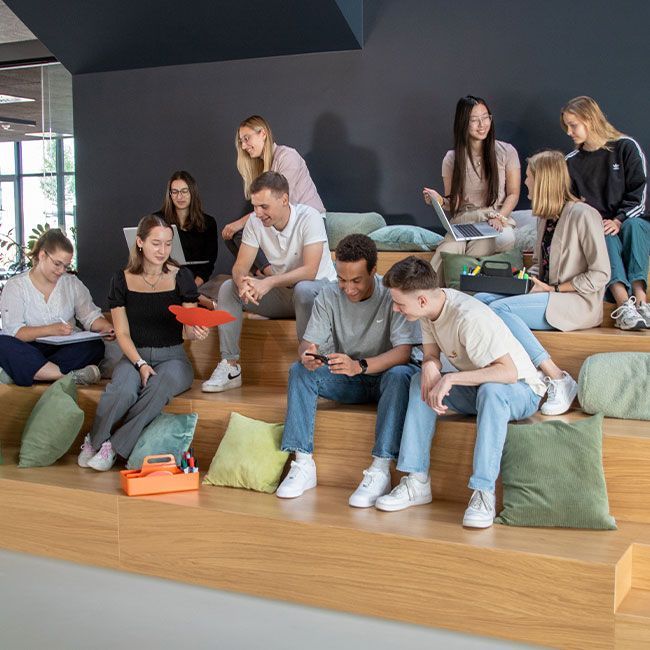 Auszubildende und duale Studenten von Streit Service & Solution sitzen zusammen auf einer Treppe und sprechen miteinander