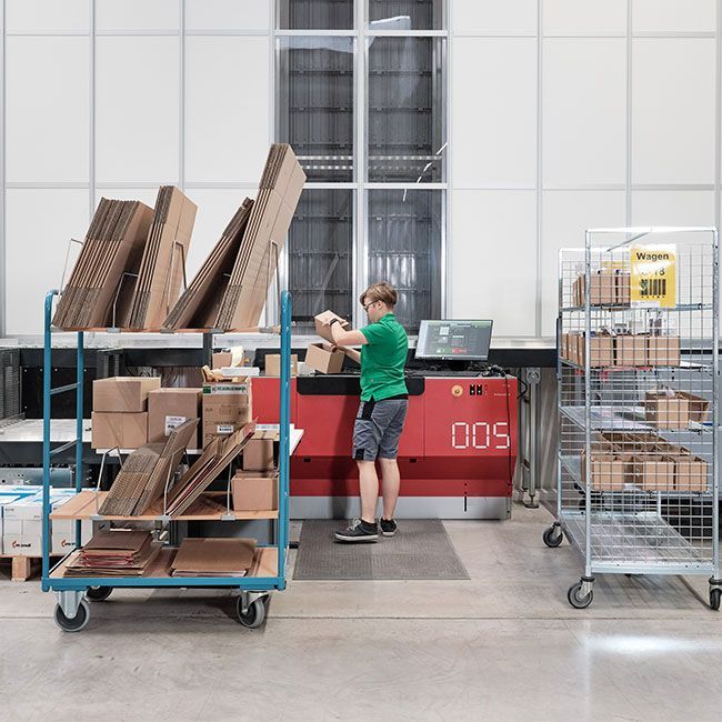 Mitarbeiterin von Streit Service & Solution packt im Logistikzentrum ein Paket an der AutoStore Anlage.