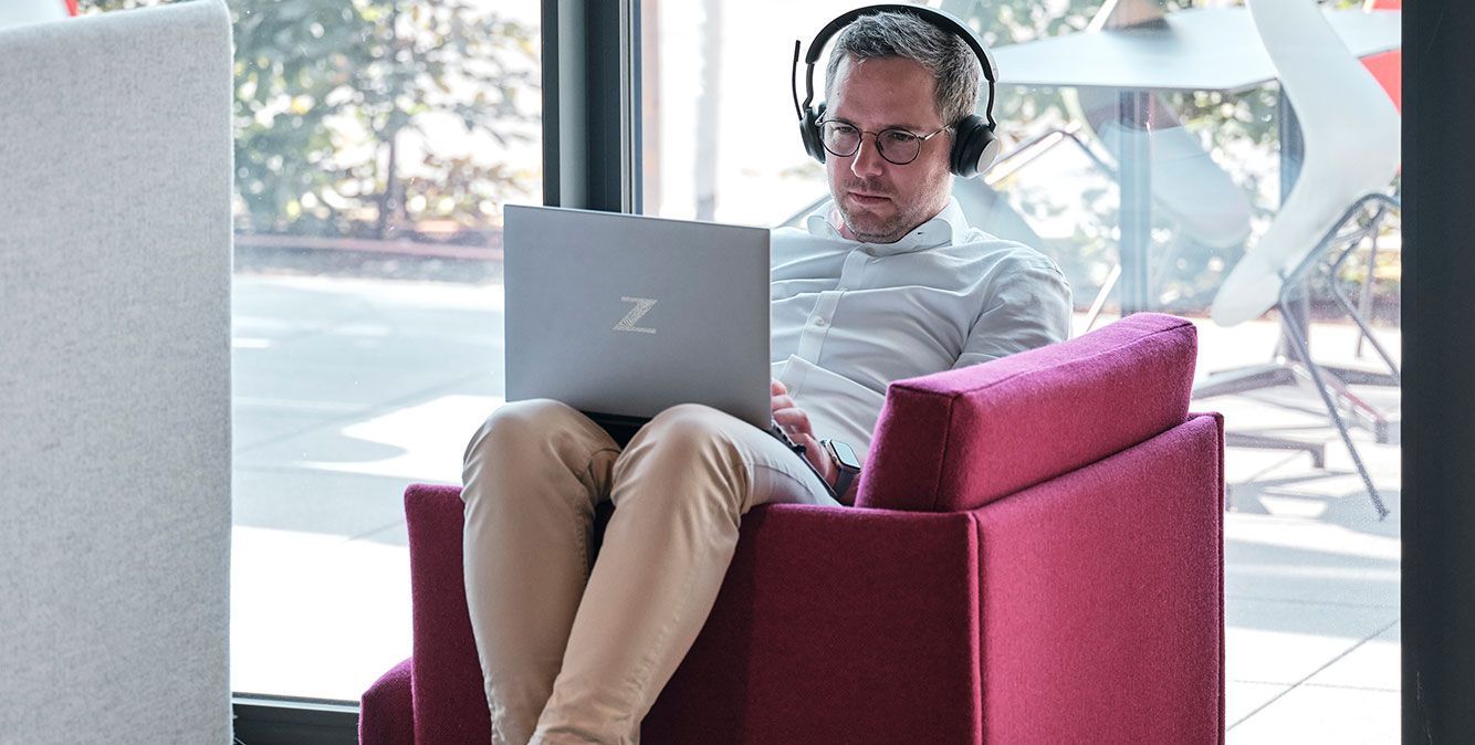 Mitarbeiter von Streit Service & Solution sitzt im Homeoffice im Sessel und arbeitet am Laptop