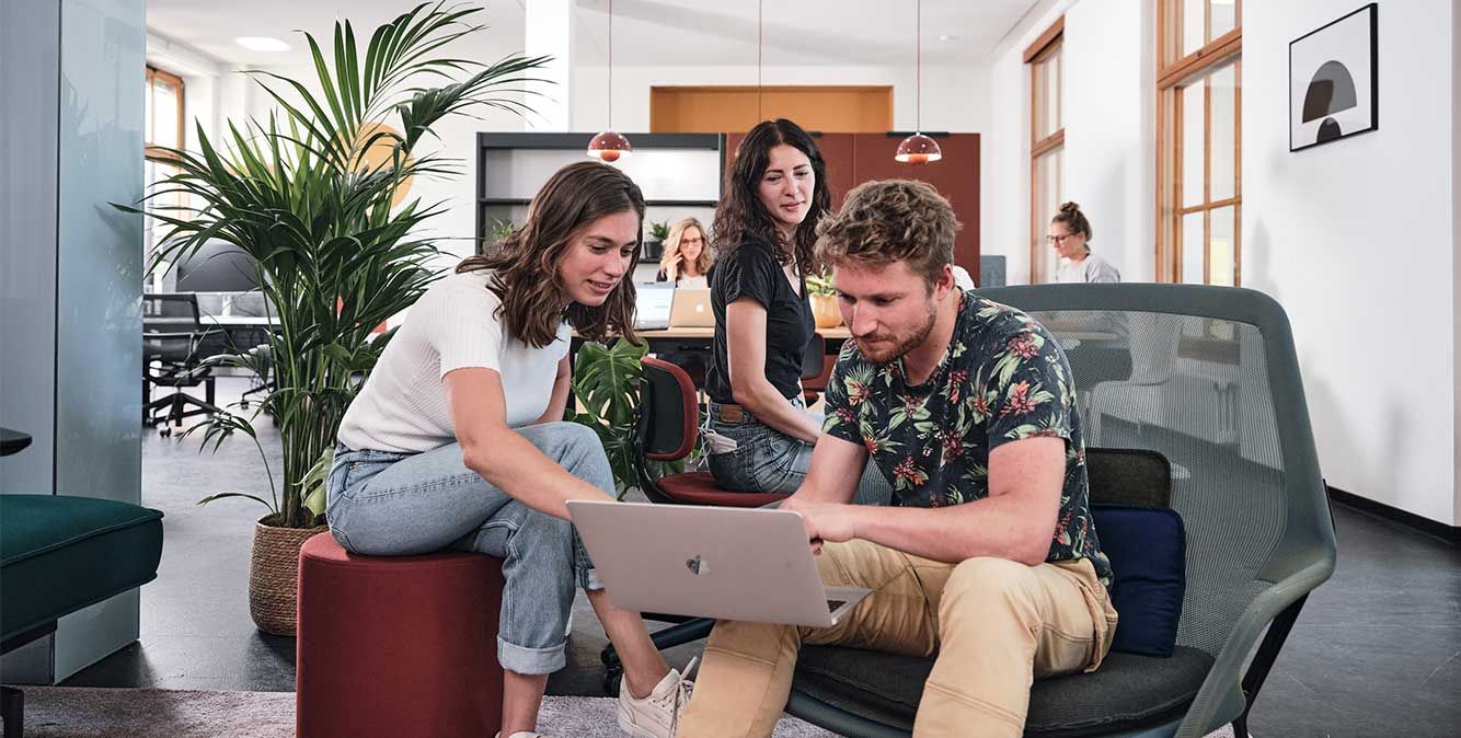 Mitarbeiter sitzen zusammen und arbeiten gemeinsam an einem Laptop