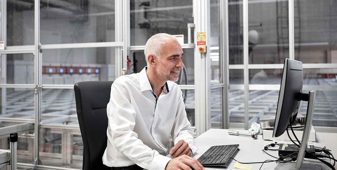 Person vor PC am Arbeiten in Logistikhalle