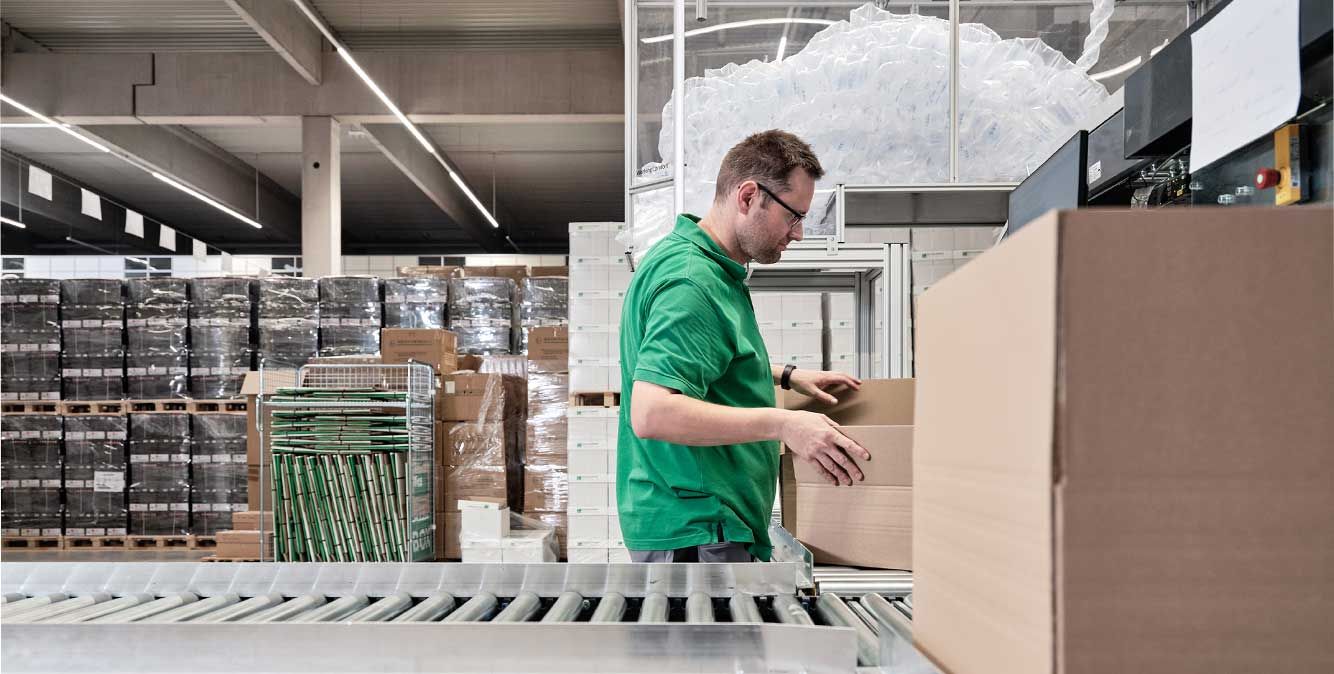 Mitarbeiter von Streit Service & Solution packt im Logistikzentrum ein Packet mit Luftposterfolie