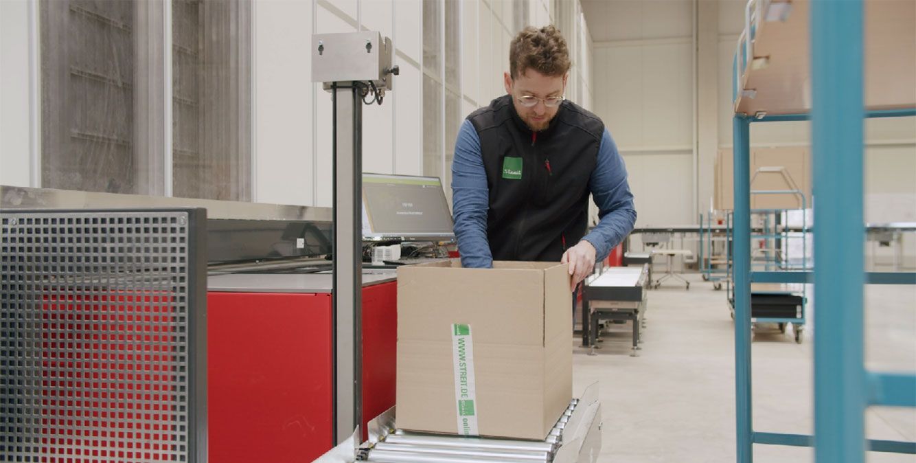Mitarbeiter von Streit Service & Solution packt ein Packet im Logistikzentrum in Gengenbach