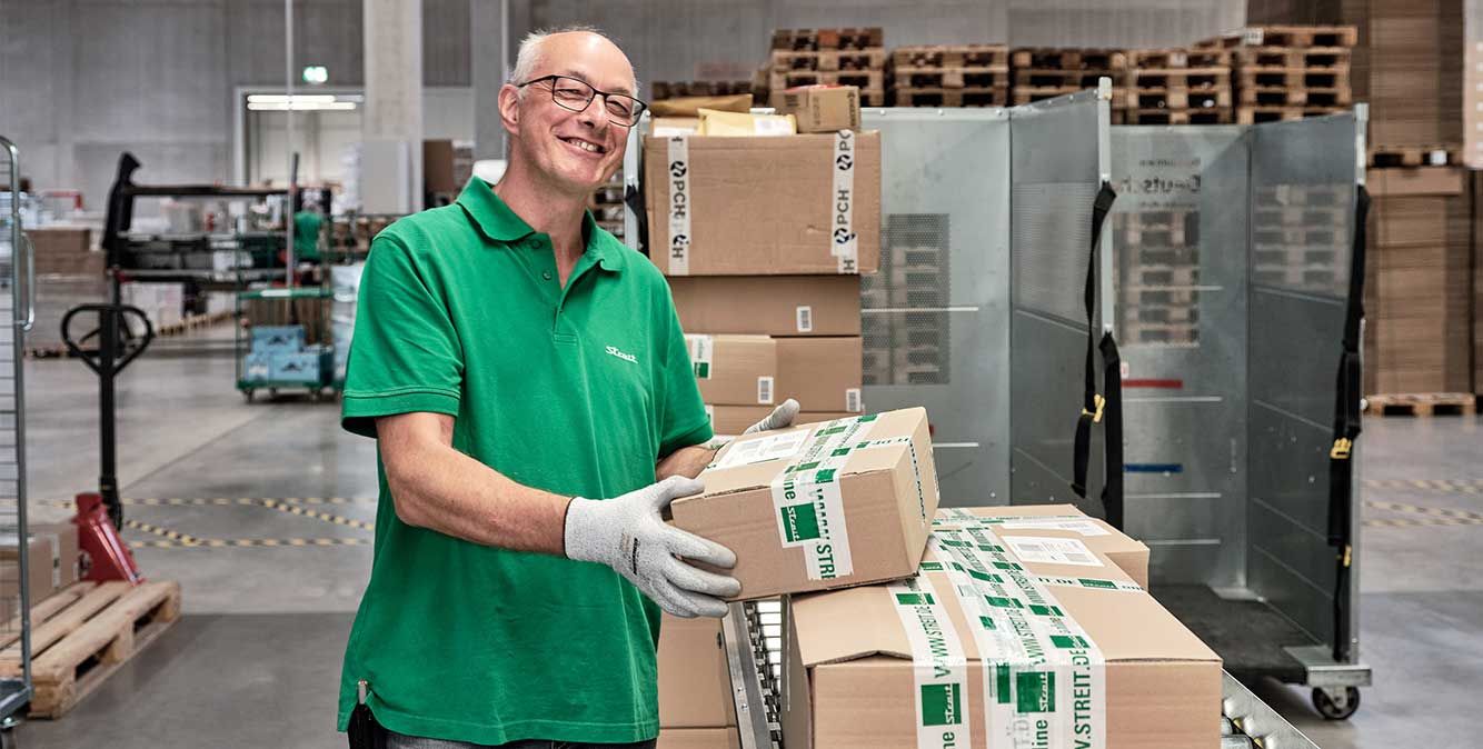 Mitarbeiter von Streit Service & Solution verladet Pakete im Logistikzentrum in Gengenbach