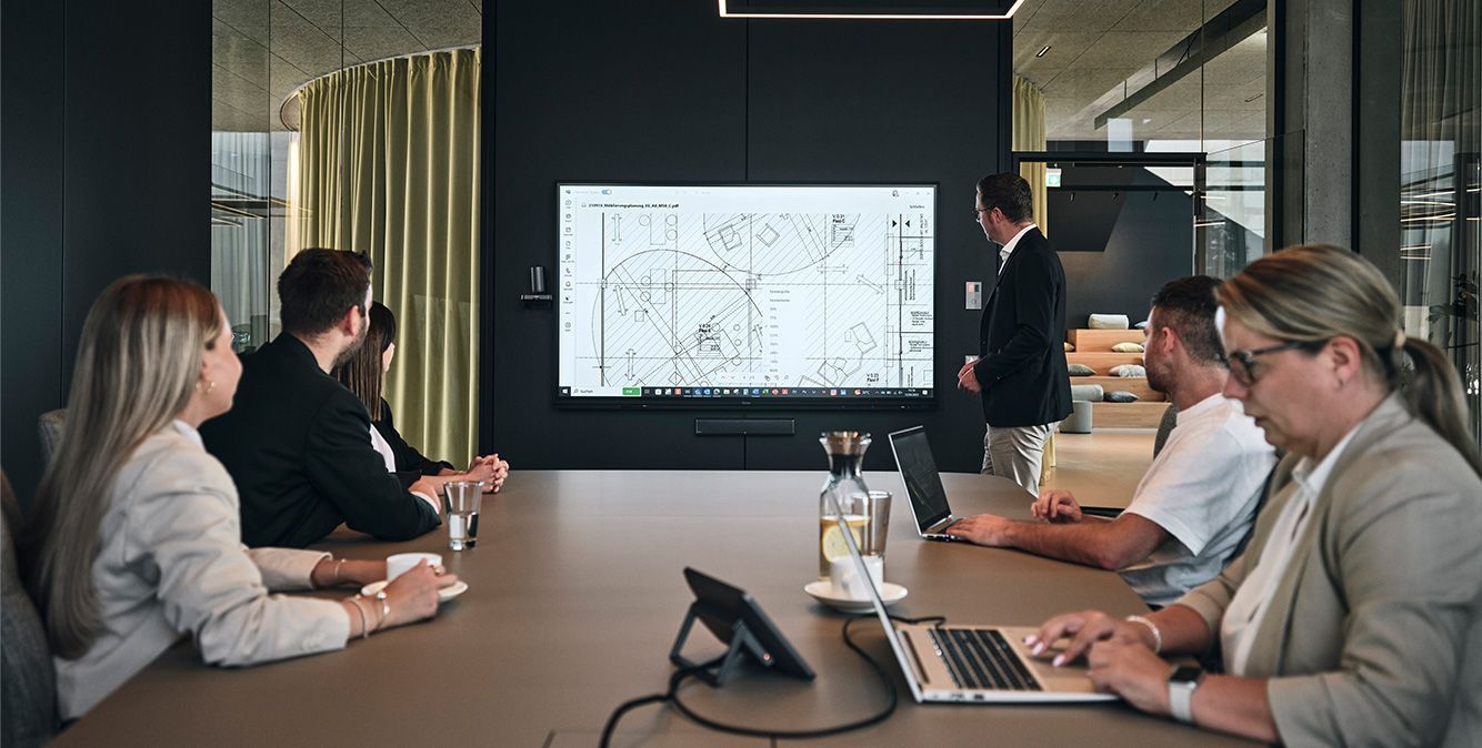 Mitarbeiter von Streit Service & Solution sitzen in einem Besprechnungsraum und nutzen die Medientechnik vor Ort