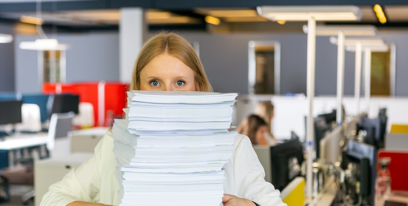 Mitarbeiterin von Streit Service & Solution steht hinter einem Stapel Papier