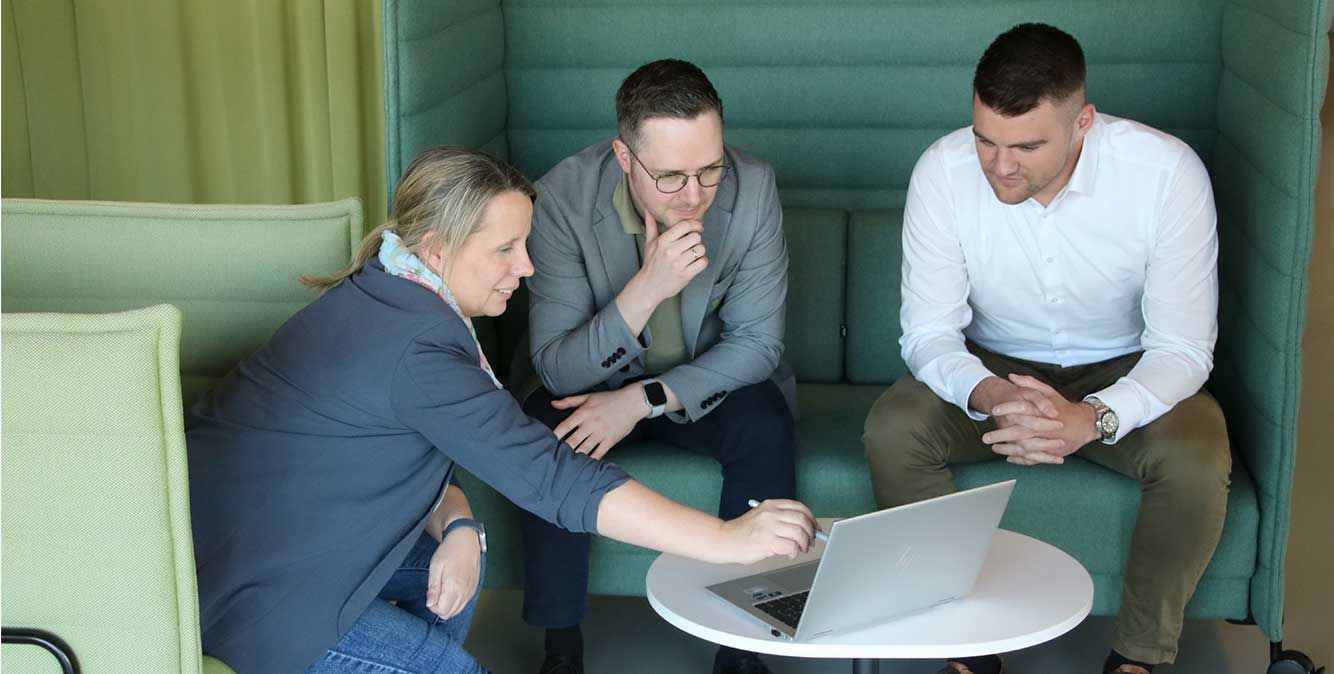 Mitarbeiter von Streit Service & Solution sitzen zusammen und schauen in einen Laptop
