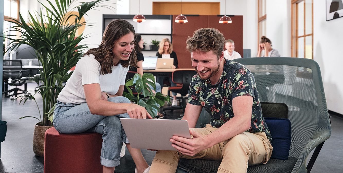 Zwei Personen schauen sitzen zusammen und schauen zusammen in einen Laptop