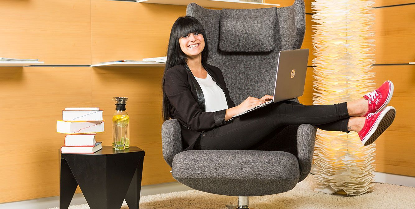 Mitarbeiterin von Streit Service & Solution sitzt im Sessel und arbeitet am Laptop