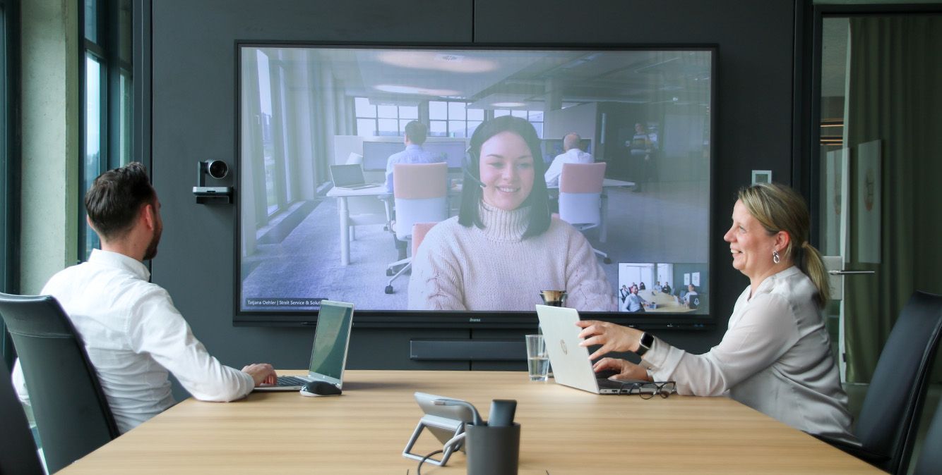 Mitarbeiter von Streit Service & Solution sitzen zusammen in einem Besprechungsraum und sprechen per Videokonferenz mit einer weiteren Person
