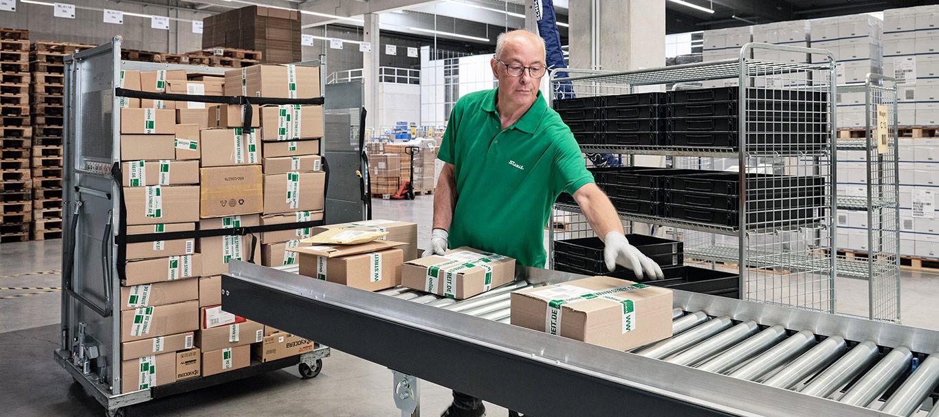 Mitarbeiter stapelt Pakete im Logistikzentrum von Streit Service & Solution in Gengenbach