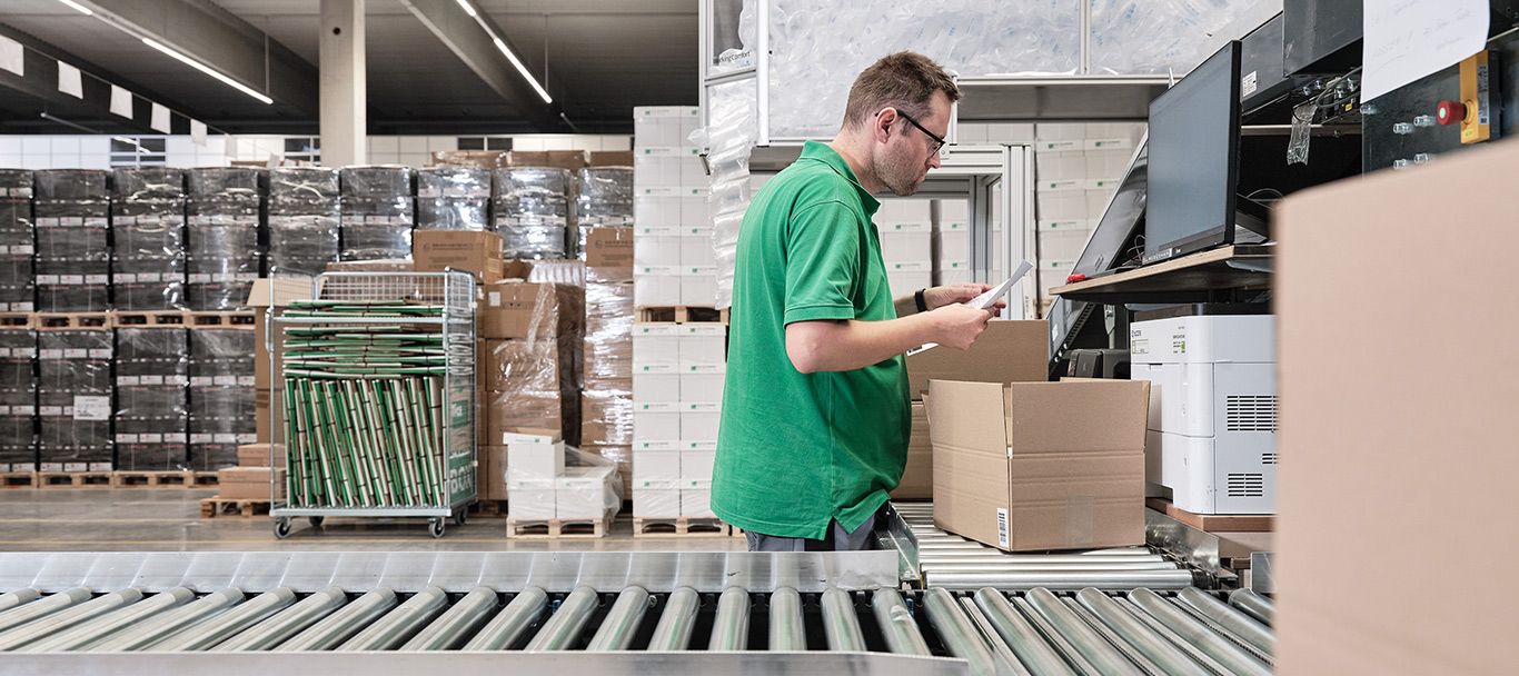 Mitarbeiter packt ein Paket an der Packstation im Logistikzentrum von Streit Service & Solution in Gengenbach