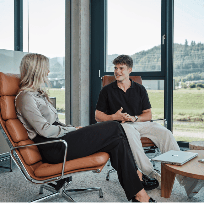 Zwei Mitarbeiter von Streit Service & Solution sitzen nebeneinander und sprechen miteinander