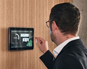 Mitarbeiter von Streit Service & Solution bedient das Raumbuchungspanel vor dem Konferenzraum