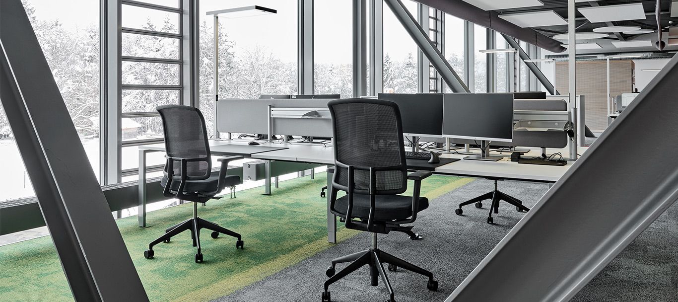 Ergonomischer Arbeitsplatz mit Schreibtischen und Drehstühlen