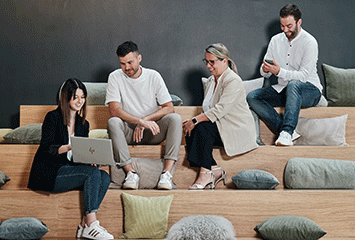 Mitarbeiter von Streit Service & Solution sitzen gemeinsam auf einer Treppe und arbeiten und sprechen miteinander