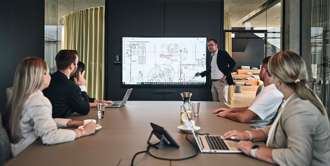 Mitarbeiter von Streit Service & Solution arbeiten zusammen in einem Besprechungsraum. Am Bildschirm wird etwas präsentiert