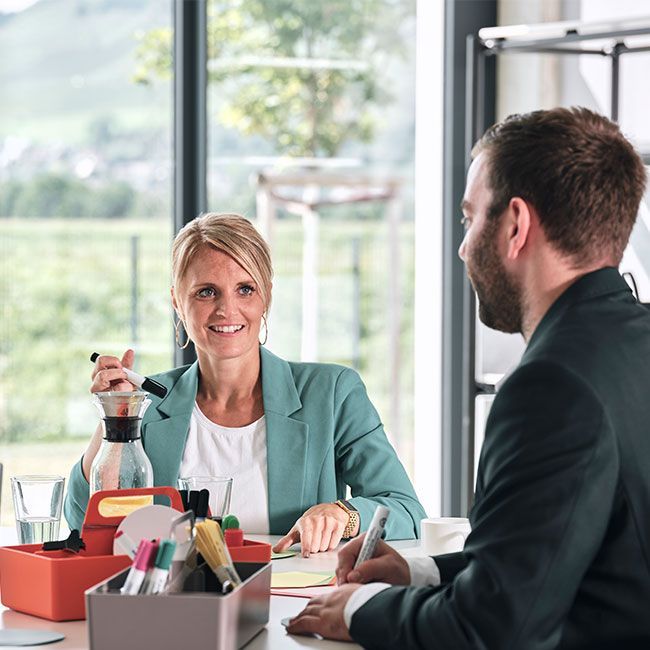Mitarbeiter von Streit Service & Solution arbeiten zusammen an einem Tisch und sprechen miteinander