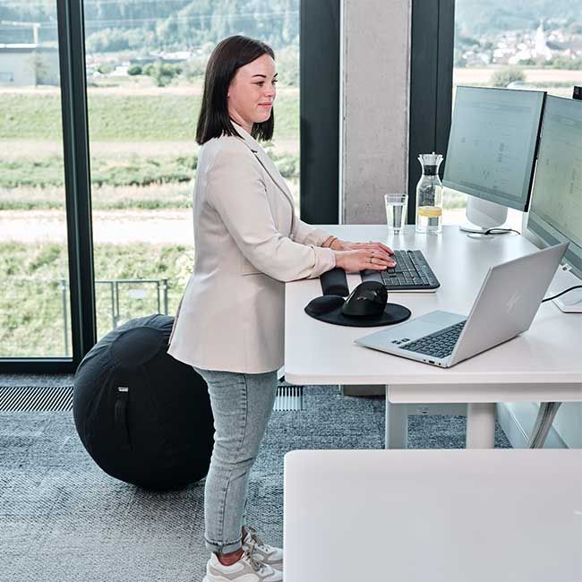 Mitarbeiterin von Streit Service & Solution steht an ihrem Arbeitsplatz und tippt auf der Tastatur.
