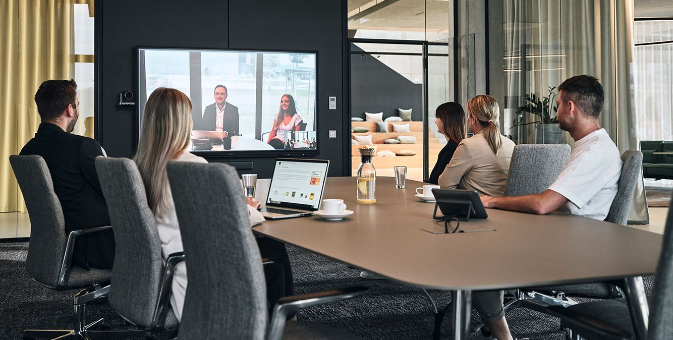 Mitarbeiter von Streit Service & Solution sitzen zusammen in einem Konferenzraum und nehmen an einer Videokonferenz teil