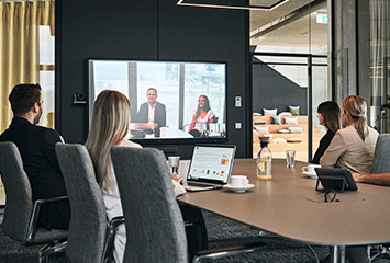 Mitarbeiter von Streit Service & Solution sitzen zusammen in einem Konferenzraum und nehmen an einer Videokonferenz teil