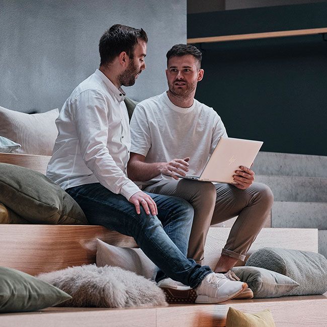 Mitarbeiter von Streit Service & Solution sitzen zusammen auf einer Treppe und arbeiten am Laptop