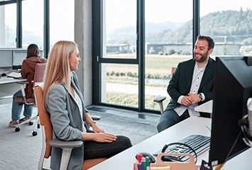 Mitarbeiter von Streit Service & Solution sitzen an ihrem Arbeitsplatz und sprechen miteinander