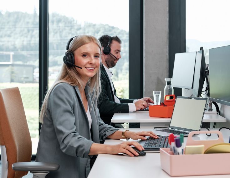 Mitarbeiter von Streit Service & Solution arbeiten am Schreibtisch und Telefonieren per Headset