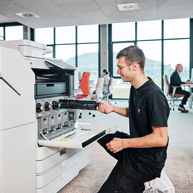 Mitarbeiter von Streit Service & Solution befüllt einen Drucker mit neuen Druckpatronen
