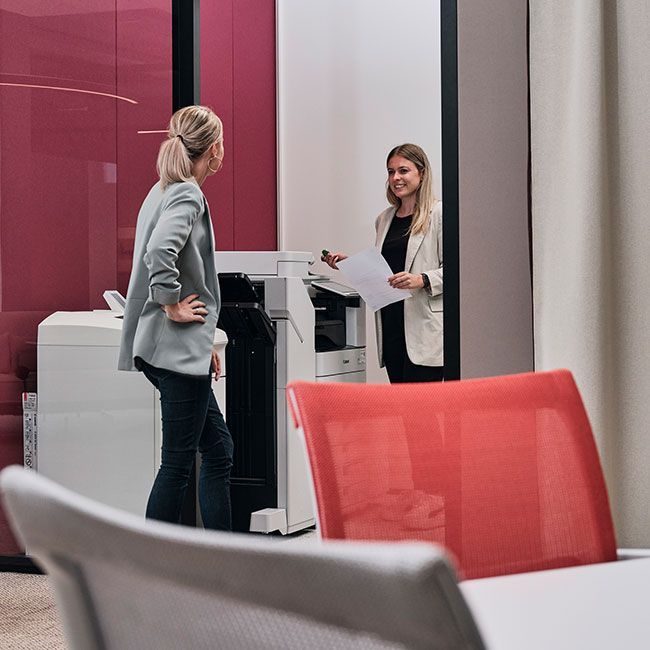 Zwei Mitarbeiterinnen von Streit Service & Solution stehen nehmen einem Druckgerät