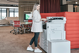 Frau steht am Drucksystem und bedient Touchpanel