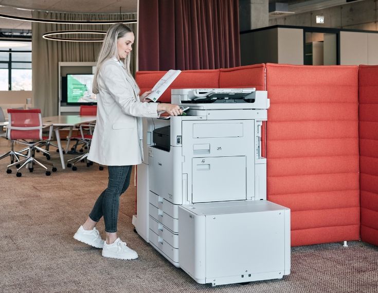Frau steht am Drucksystem und bedient Touchpanel