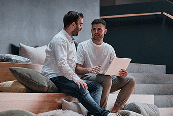 Zwei Mitarbeiter von Streit Service & Solution sitzen zusammen, unterhalten sich und arbeiten an einem Laptop