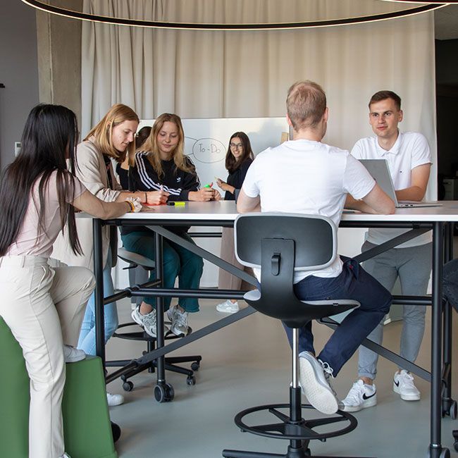 Duale Studenten von Streit Service & Solution arbeiten zusammen an einem Tisch und einen Whiteboard