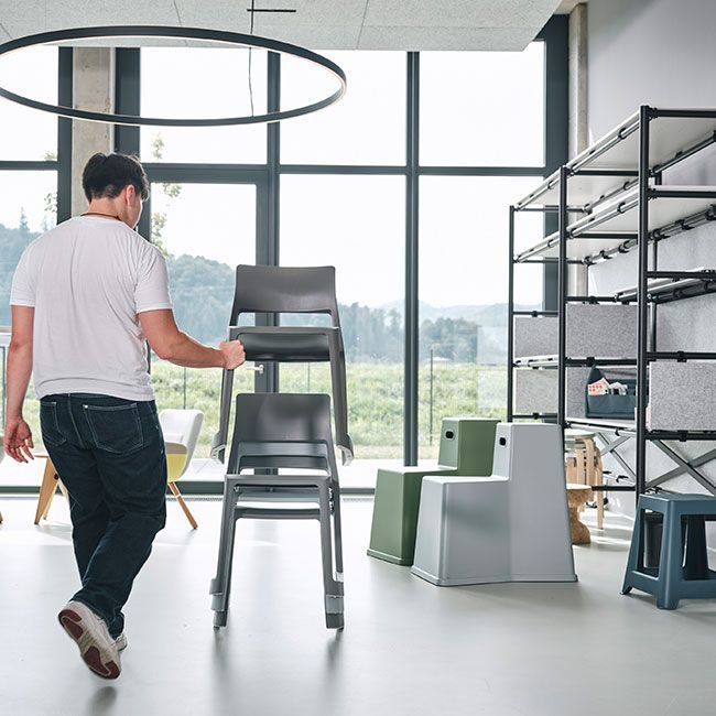 Auszubildender von Streit Service & Solution trägt einen Stuhl durch die Arbeitswelt.