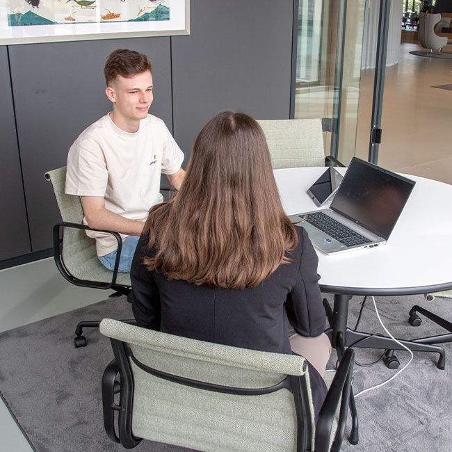 Zwei Auszubildende von Streit Service & Solution sitzen in einem Besprechungszimmer und arbeiten zusammen an einem Laptop