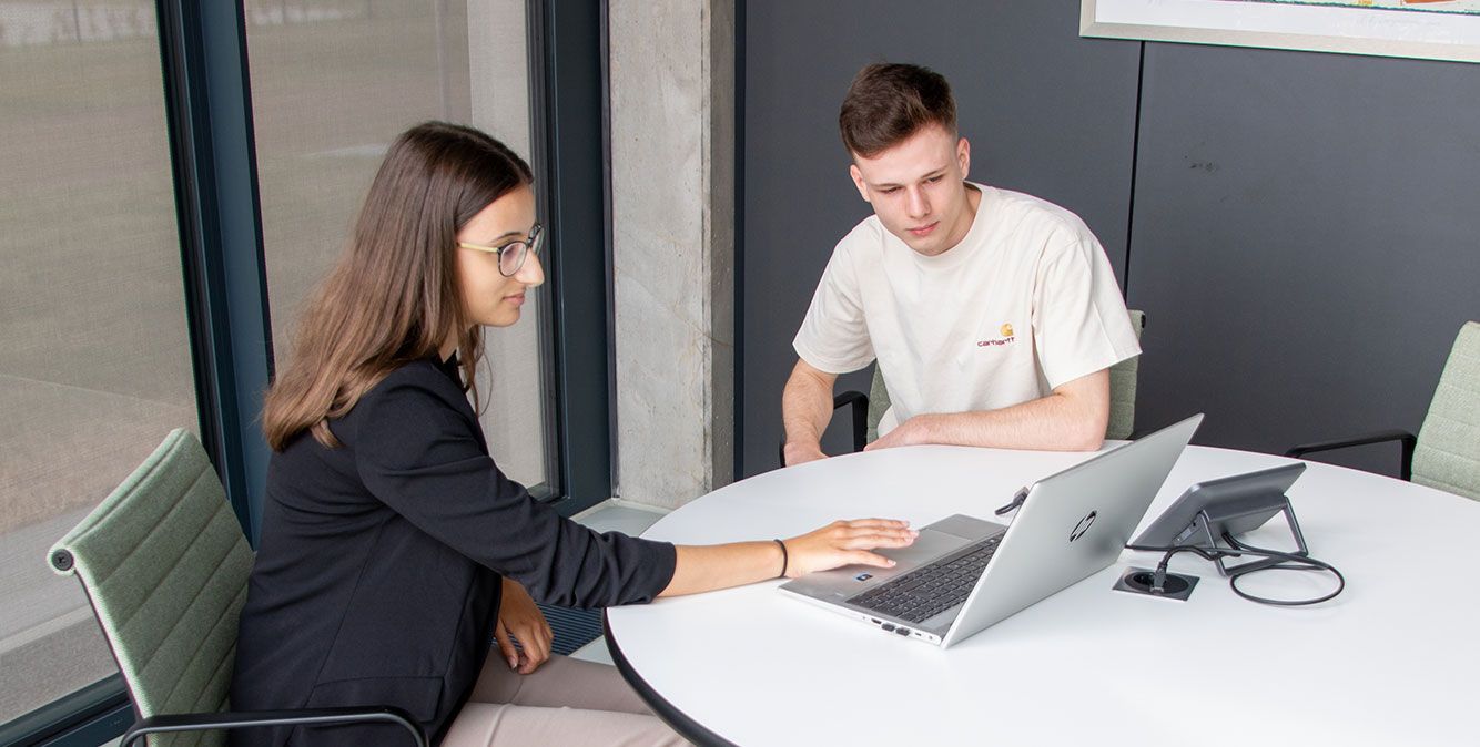 Zwei duale Studenten von Streit Service & Solution arbeiten zusammen an einem Laptop