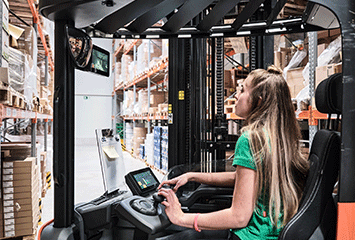 Auszubildende von Streit Service & Solution fährt in einem Stapler durchs Logistikzentrum