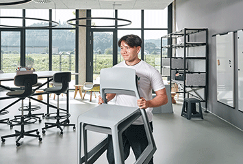 Auszubildender von Streit Service & Solution trägt Stühle durch die Arbeitswelt