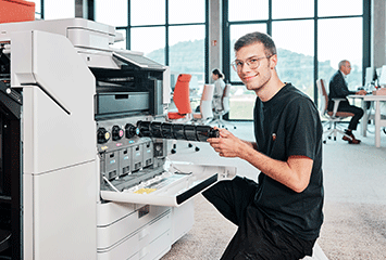 Auszubildender von Streit Service & Solution befüllt einen Drucker mit neuen Tintenpatronen