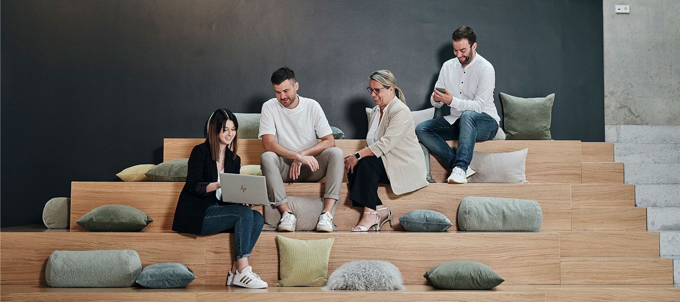 Mitarbeiter von Streit Service & Solution sitzen auf einer Treppe und arbeiten miteinender